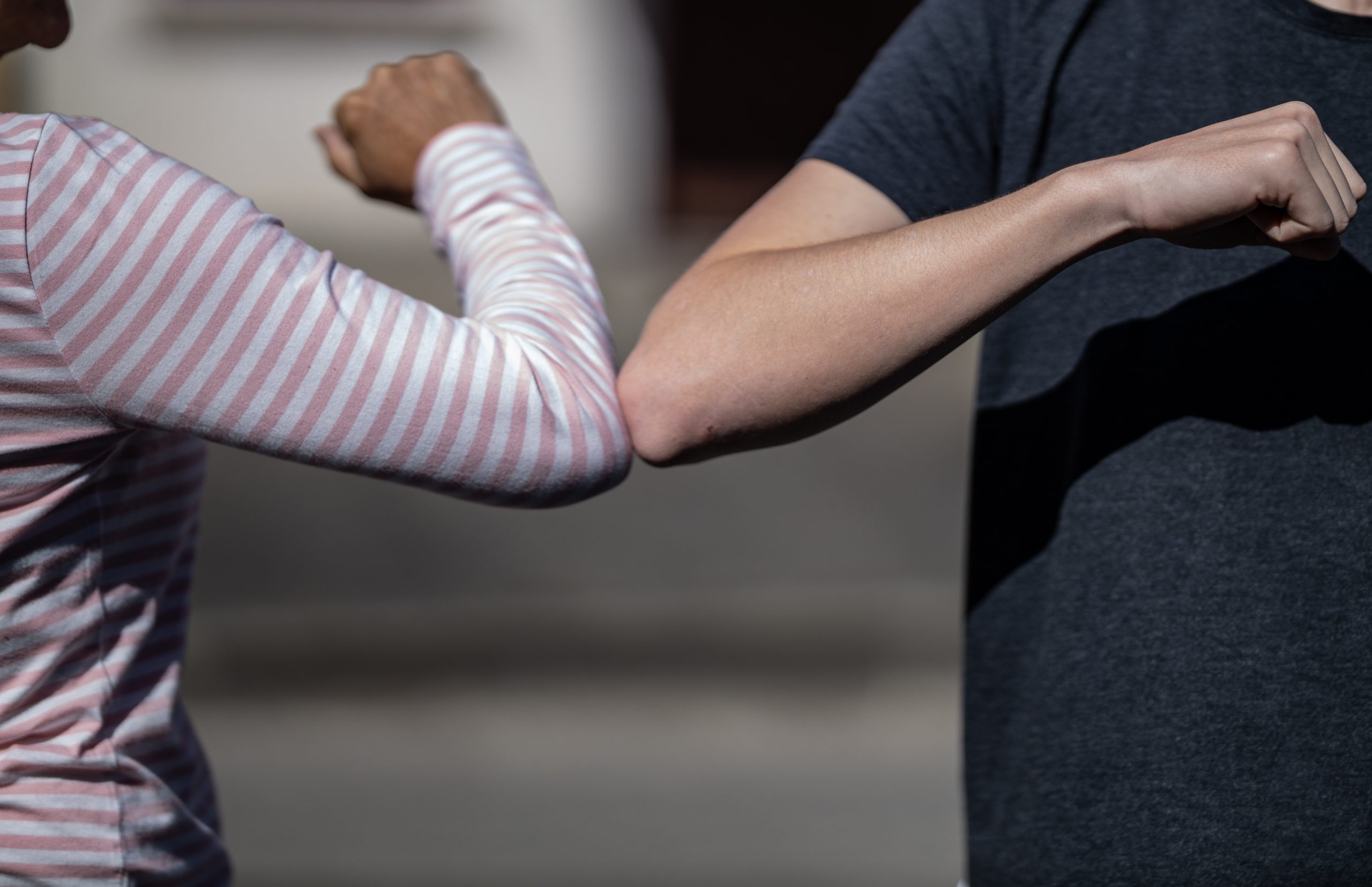 Two people bumping elbows as a greeting to reduce contact and the spread of COVID-19. 