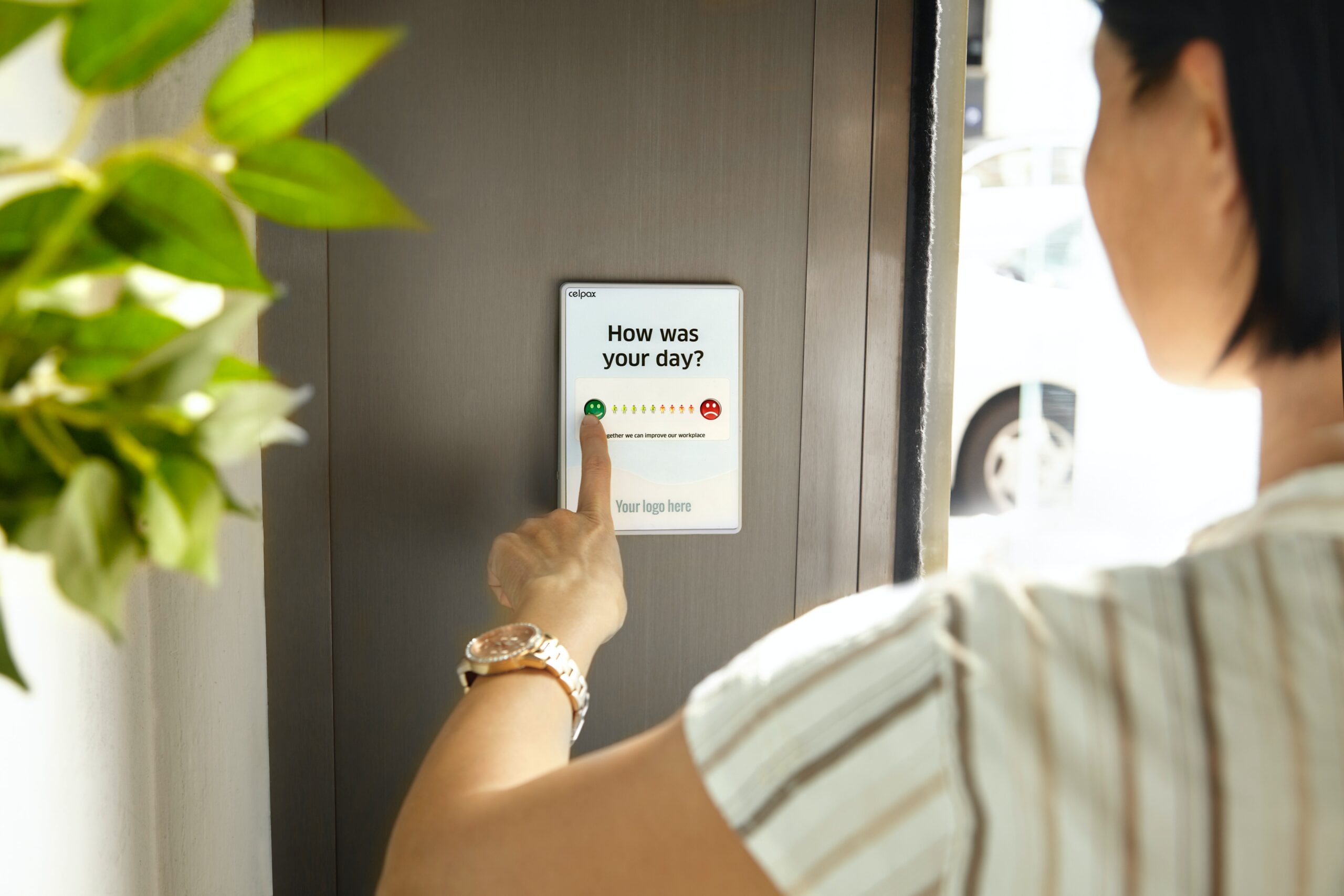 A woman completes a survey on a wall mounted screen.