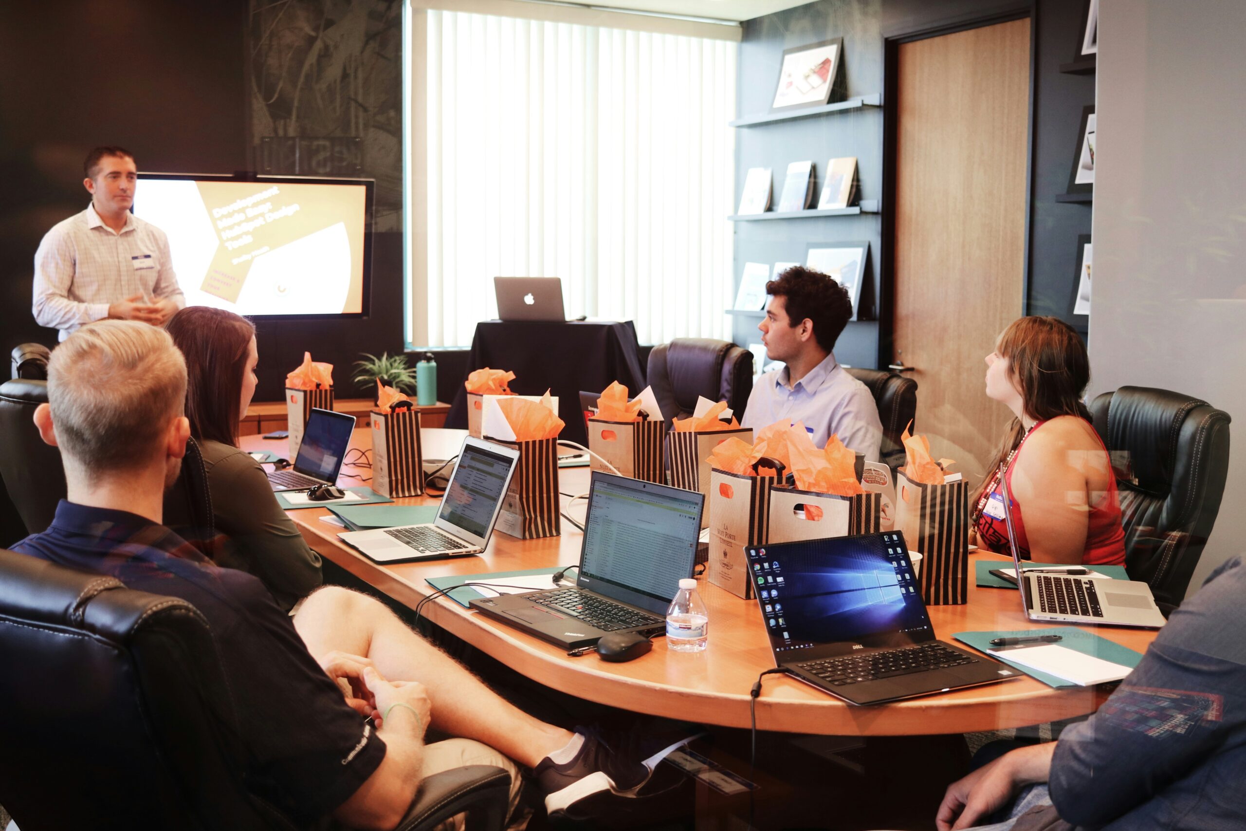 Students with laptops open around a table gathering for class.